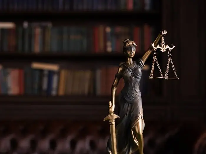 Lady Justice and gavel on a table in a classic law library setting.